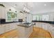 Bright kitchen features white cabinetry, black countertops, stainless appliances, a large island with cooktop and hardwood floors at 2112 Murren Se Dr, Smyrna, GA 30080
