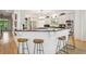 Open concept kitchen has an island with seating, a breakfast bar, stainless appliances, white cabinetry and hardwood flooring at 2112 Murren Se Dr, Smyrna, GA 30080