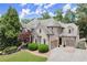 A charming brick home with manicured landscaping, a circular driveway, and a three-car garage under a blue sky at 4105 Cougar Ne Pt, Marietta, GA 30066