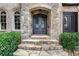 Stone steps lead to the detailed iron double doors of this home, flanked by manicured shrubs and arched windows at 4105 Cougar Ne Pt, Marietta, GA 30066