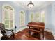 A cozy living room with a hardwood floor features a grand piano and large windows fitted with white shutters at 4105 Cougar Ne Pt, Marietta, GA 30066