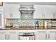 Modern kitchen with granite countertops, stainless steel appliances, white cabinets, and a stylish backsplash at 1253 Rivermark Ct, Lawrenceville, GA 30043