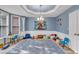 Spacious playroom featuring blue walls with white trim, decorative ceiling and a large patterned rug at 1253 Rivermark Ct, Lawrenceville, GA 30043