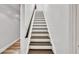 Well-lit staircase with wooden treads and white risers, connecting the home's levels at 1253 Rivermark Ct, Lawrenceville, GA 30043