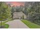 Charming two-story home featuring a manicured lawn and a long driveway under a beautiful sunset sky at 2740 Creekside Manor Dr, Powder Springs, GA 30127