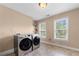 Modern laundry room with front loading washer and dryer and two bright windows at 2740 Creekside Manor Dr, Powder Springs, GA 30127