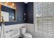 Elegant powder room featuring white wainscoting, blue walls, and a gold-trimmed mirror at 1251 Brickton Nw Dr, Atlanta, GA 30318
