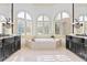 Luxurious bathroom features dual vanities, a soaking tub, and arched windows with plantation shutters at 8370 Royal Melbourne Way, Duluth, GA 30097