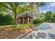 Back exterior featuring a house with a wooden balcony, green lawn, mature landscaping, and sidewalk at 11259 Calypso Dr, Alpharetta, GA 30009