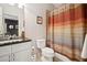 Bright bathroom with a modern vanity, granite countertop, toilet, and a shower with a colorful striped curtain at 11259 Calypso Dr, Alpharetta, GA 30009