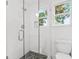 Bright bathroom boasting a glass-enclosed shower with white tile and pebble flooring, next to a toilet and window at 2296 N Shallowford Rd, Atlanta, GA 30341