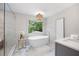 A modern bathroom with a freestanding tub, marble floors, and a large window providing natural light at 3702 Running Fox Dr, Marietta, GA 30062