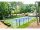 Fenced tennis court surrounded by mature trees and lush green space in a vibrant community at 3702 Running Fox Dr, Marietta, GA 30062