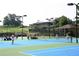Active tennis court with players, surrounded by lush greenery and a clubhouse in the background at 11785 Mountain Laurel Dr, Roswell, GA 30075
