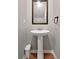 Classic powder room with a pedestal sink, framed mirror, and wooden floors at 301 Amsterdam Way, Hampton, GA 30228