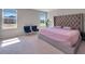 Bright bedroom with a tufted headboard, natural light, and two chairs near a window at 301 Amsterdam Way, Hampton, GA 30228