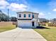 Charming two-story home featuring a well-manicured lawn and a long driveway leading to a two-car garage at 301 Amsterdam Way, Hampton, GA 30228