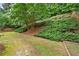 Lush backyard features mature trees, sloped landscaping, and a charming wooden fence at 4360 Canterbury Walk Dr, Duluth, GA 30097