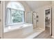Bright bathroom with a large soaking tub under a window, and a glass-enclosed shower at 4360 Canterbury Walk Dr, Duluth, GA 30097