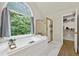 Bathroom featuring a tub under an arched window, a glass shower and walk in closet at 4360 Canterbury Walk Dr, Duluth, GA 30097