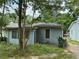 Back of a light blue single-story house, showing a simple facade and an overgrown, gravel backyard at 501 Holly Nw St, Atlanta, GA 30318