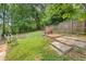 Lush backyard with a stone patio area, fire pit, mature trees and a wooden fence at 6771 Sunny Brook Ln, Atlanta, GA 30328