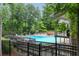 Large community pool surrounded by lounge chairs, mature trees, and fencing at 85 Dunwoody Springs Dr, Sandy Springs, GA 30328