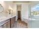 Bathroom showcasing a freestanding tub by a window, double vanity, quartz countertop, and wood-look tile flooring at 100 Percheron Dr, Canton, GA 30114