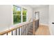 Bright hallway featuring hardwood floors, wood and iron railings, and a window view of lush greenery at 1697 Thomas St, Decatur, GA 30032