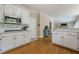 Well-lit kitchen with white cabinets, hardwood floors, stainless microwave, and an open view into the living room at 1765 Pinetree Pass Lane Southwest Sw Ln, Lilburn, GA 30047