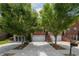 Charming brick townhome featuring a two-car garage, mature trees, and a welcoming front porch at 2264 Ewell Park Dr, Lawrenceville, GA 30043