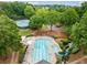 An aerial view of the community pool with a water slide and tennis courts surrounded by mature trees at 795 Lake Medlock Dr, Alpharetta, GA 30022