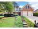 Charming brick home featuring a two-car garage, landscaped front yard, and inviting entryway with steps at 795 Lake Medlock Dr, Alpharetta, GA 30022