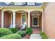 Inviting front entrance showcasing a brick facade, covered porch, and manicured landscaping at 795 Lake Medlock Dr, Alpharetta, GA 30022