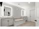 Bright bathroom featuring double vanity, soaking tub, decorative mirrors, and modern fixtures at 420 Banbury Xing, Alpharetta, GA 30009