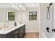 Bright bathroom featuring double vanity with gold fixtures, hardwood floors, and sleek shower/tub combo at 5759 Albans Way, Lithonia, GA 30058