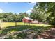 Red barn with white trim and metal roof surrounded by greenery, enclosed by a fence at , Social Circle, GA 30025