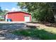 Red barn-style building with a garage door next to a stone fire pit with a gravel parking area at , Social Circle, GA 30025