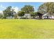 Expansive green lawn with mature trees, outbuildings, and white house in the background under a blue sky at , Social Circle, GA 30025