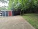 Long driveway leading to a carport and storage shed surrounded by mature trees at 3226 Hope St, Hapeville, GA 30354