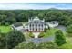 Expansive white home featuring a green roof, black chimneys and shutters, manicured landscaping and a circular driveway at 2595 Ross Rd, Snellville, GA 30039