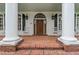 This home features a brick front porch with grand white columns, shutters, rocking chairs and a beautiful wooden door at 2595 Ross Rd, Snellville, GA 30039