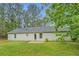View of the home's backyard, showcasing a well-kept lawn and neutral-toned exterior nestled among lush greenery at 4547 Atha Cir, Loganville, GA 30052
