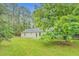 Backyard view shows the home's exterior with a patio and lush green lawn, all surrounded by mature trees at 4547 Atha Cir, Loganville, GA 30052