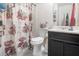 Bathroom with a floral shower curtain, toilet, sink, and vanity, creating a functional and private space at 556 Country Greens Dr, Jonesboro, GA 30238