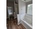 Bathroom features a tub with tile surround, wood-look flooring, and natural light from the window at 165 Heaton Place Trl, Covington, GA 30016