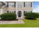 Inviting home entrance with a decorative door, complemented by manicured shrubs and green grass at 165 Heaton Place Trl, Covington, GA 30016