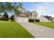 Traditional home with two-car garage and driveway, surrounded by a green lawn and mature trees at 165 Heaton Place Trl, Covington, GA 30016