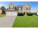Charming two-story home with a manicured lawn and a two-car garage on a sunny day at 165 Heaton Place Trl, Covington, GA 30016
