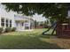 Spacious backyard with a covered patio, lush green lawn, and a wooden playset at 2029 Havenhurst Way, Auburn, GA 30011
